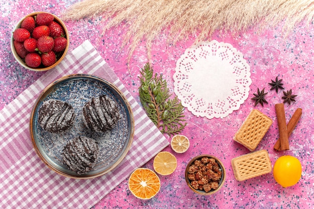 Draufsicht leckere Schokoladenkuchen mit frischen roten Erdbeeren auf rosa