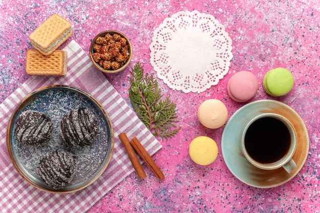 Draufsicht leckere Schokoladenkuchen mit Tasse Tee und Macarons auf rosa