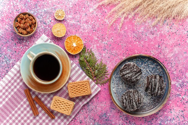 Draufsicht leckere Schokoladenkuchen mit Tasse Tee Waffeln auf rosa