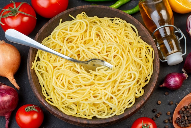 Draufsicht leckere Spaghetti in Schüssel Tomaten Öl Flasche Zwiebeln auf dem Tisch