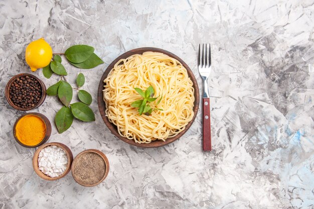 Draufsicht leckere Spaghetti mit Gewürzen auf weißem Teig Nudelgericht