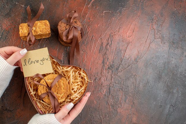 Draufsicht leckere süße Kekse in herzförmiger Schachtel auf dunklem Hintergrund Ehegefühl Paar Geschenk Farbe Liebe Urlaub