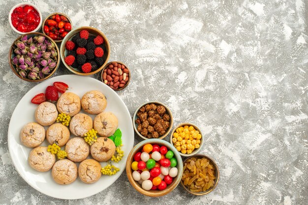 Draufsicht leckere süße Kekse mit Bonbons und Nüssen auf weißem Hintergrund Süßigkeitenplätzchenkeks süßer Teezucker