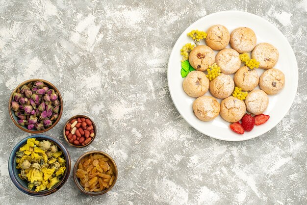 Draufsicht leckere süße Kekse mit Nüssen und Rosinen auf weißem Hintergrundzuckerkuchenplätzchenbonbon