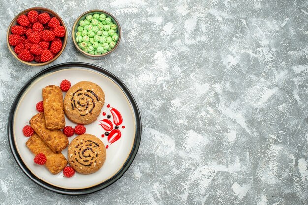 Draufsicht leckere süße Kekse mit Süßigkeiten auf weißem Hintergrundkeks süßer Zuckerkuchen-Kekstee