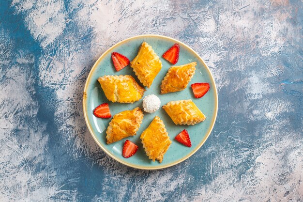 Draufsicht leckere süße Kuchen mit Erdbeeren auf blauem Hintergrund