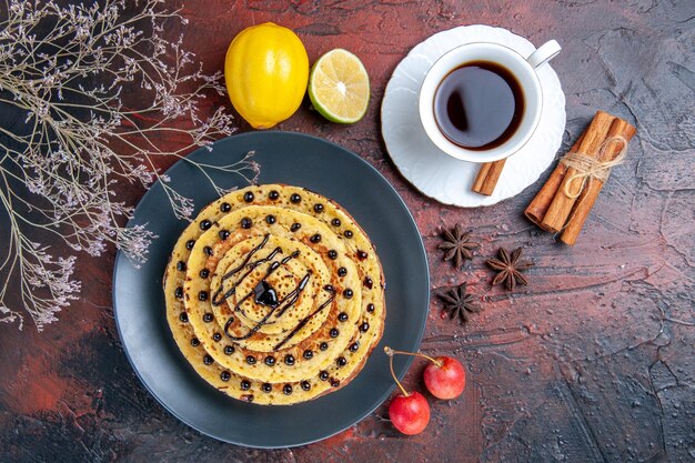 Draufsicht leckere süße Pfannkuchen mit Tee auf der dunklen Oberfläche