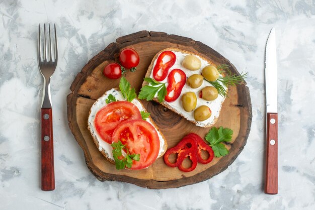 Draufsicht leckere Toasts mit Tomaten und Oliven auf Holzbrett mit weißem Hintergrund Brot Burger Snack horizontales Sandwich Essen Abendessen