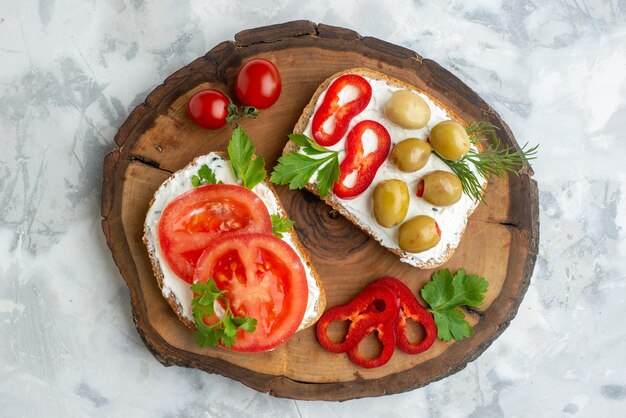 Draufsicht leckere Toasts mit Tomaten und Oliven auf Holzbrett mit weißem Hintergrund Burgerbrot Mahlzeit horizontales Essen Abendessen Mittagessen Sandwich