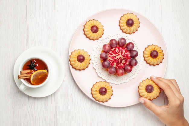 Draufsicht leckere Traubenkuchen mit Tasse Tee auf weißem Tischdessert-Keks-Kuchen-Keks