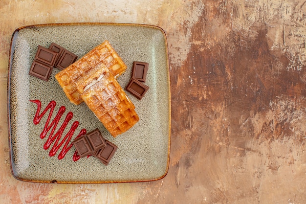 Draufsicht leckere Waffelkuchen mit Schokoriegeln auf braunem Hintergrund