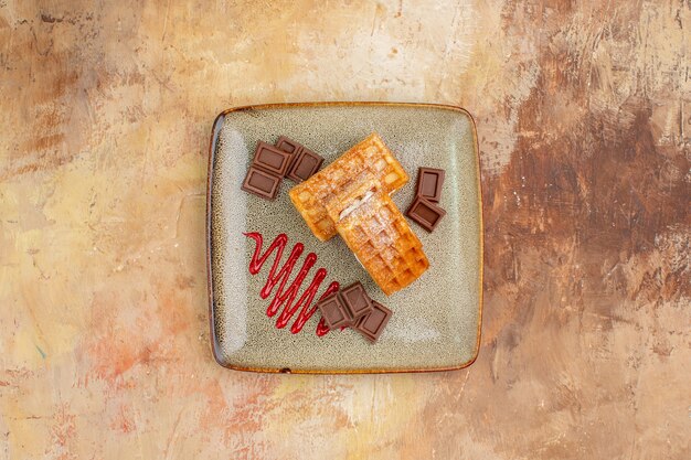 Draufsicht leckere Waffelkuchen mit Schokoriegeln auf braunem Hintergrund