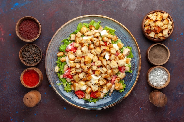 Draufsicht leckeren Caesar Salat mit verschiedenen Gewürzen auf der dunklen Oberfläche