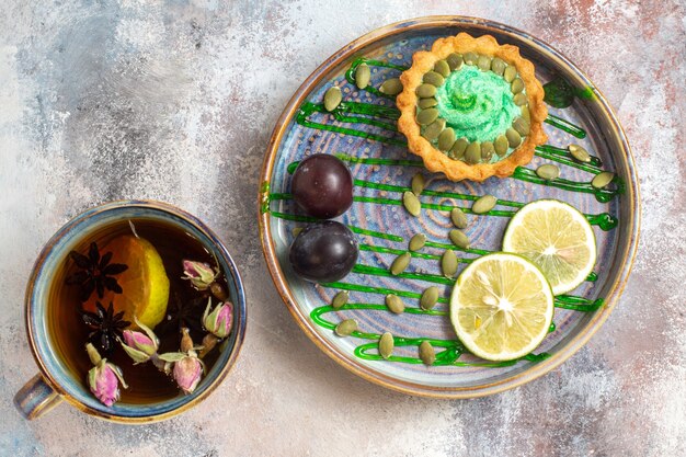 Draufsicht leckeren cremigen Kuchen mit Tasse Tee auf hellem Hintergrund süßer Bonbonkeks