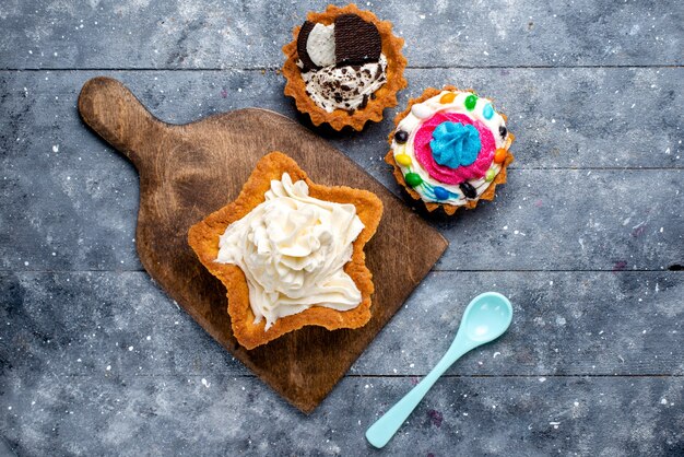 Draufsicht leckeren cremigen Kuchenstern geformt mit Plätzchenkuchen und blauem Löffel auf dem hellen Hintergrundkuchen-Kekscreme-süßen Tee