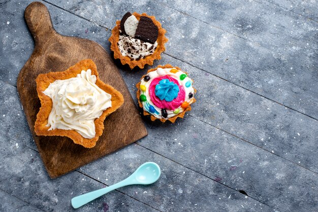 Draufsicht leckeren cremigen Kuchenstern geformt mit Plätzchenkuchen und blauem Löffel auf dem leichten Schreibtischkuchen-Kekscreme-süßen Tee