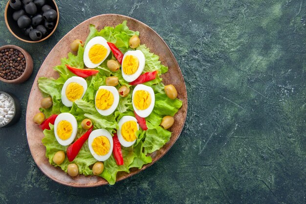 Draufsicht leckeren Eiersalat mit grünen Salatoliven und Gewürzen auf dunkelblauem Hintergrund