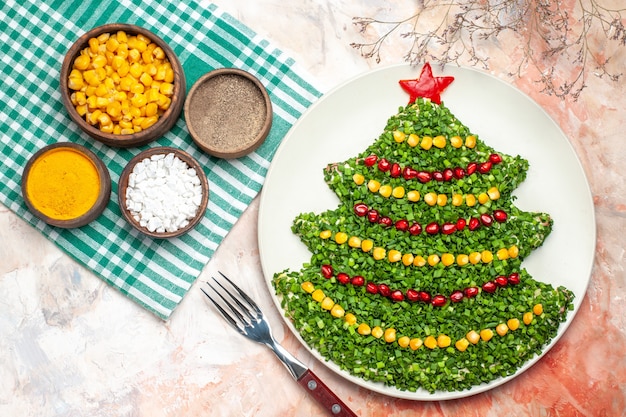 Draufsicht leckeren grünen Salat in der Neujahrsbaumform mit Gewürzen auf dem hellen Hintergrund