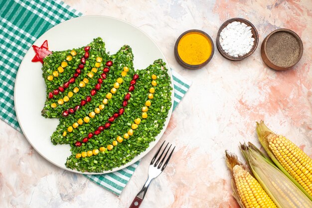 Draufsicht leckeren grünen Salat in Neujahrsbaumform mit Gewürzen auf hellem Schreibtischfarbfoto Mahlzeit Feiertagsgesundheitsweihnachten