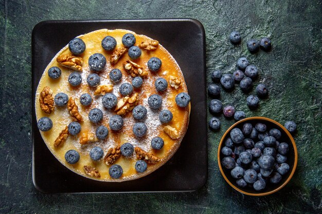 Draufsicht leckeren Honigkuchen mit Blaubeeren und Walnüssen innerhalb Platte dunkle Oberfläche