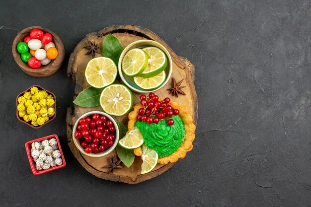 Draufsicht leckeren Kuchen mit Früchten und Süßigkeiten auf dunklem Hintergrund süßer Kekskuchen freier Platz