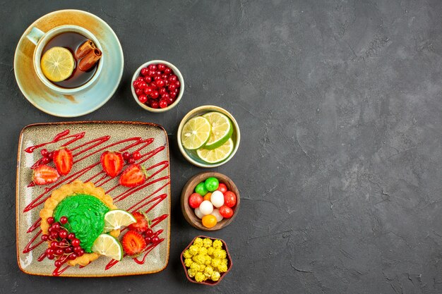 Draufsicht leckeren Kuchen mit Früchten und Tee auf grauem Hintergrundplätzchenkeks süß