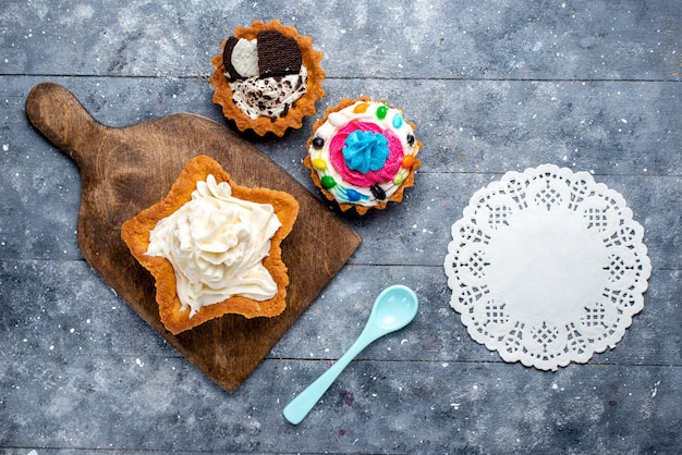 Draufsicht leckerer cremiger Kuchenstern geformt mit Plätzchenkuchen und blauem Löffel auf dem hellen Bodenkuchenkekscreme-süßer Tee