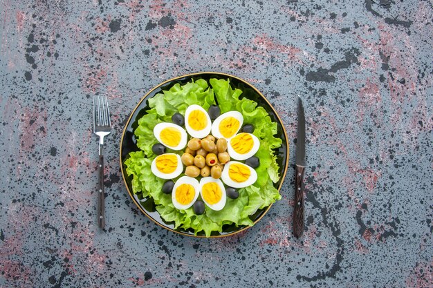 Draufsicht leckerer Eiersalat besteht aus grünem Salat und Oliven auf hellem Hintergrund