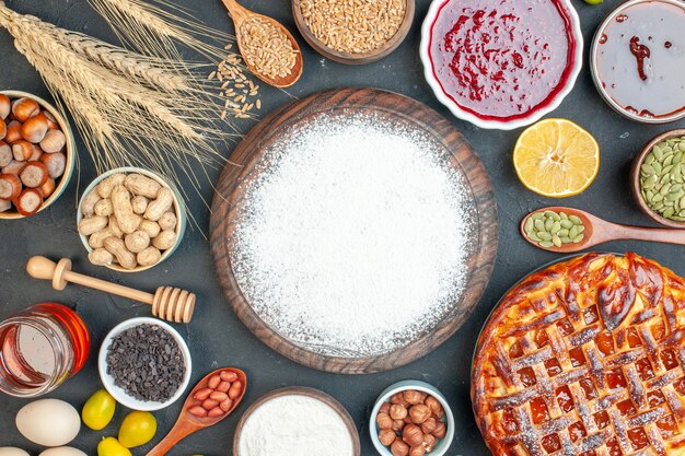 Kostenloses Foto draufsicht leckerer fruchtiger kuchen mit mehlnüssen und marmelade auf einem dunklen plätzchen süßer kuchen zuckerkuchen teegebäck dessertkeks