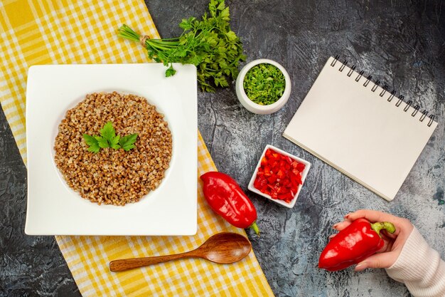 Draufsicht leckerer gekochter Buchweizen mit Gemüse und Paprika auf dem hellgrauen Tisch