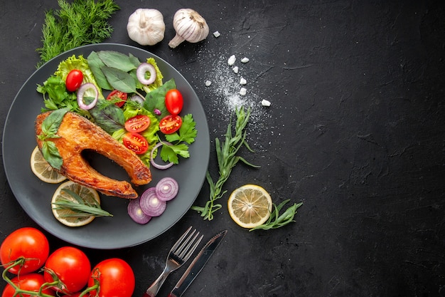 Draufsicht leckerer gekochter Fisch mit frischem Gemüse auf dem dunklen Tisch