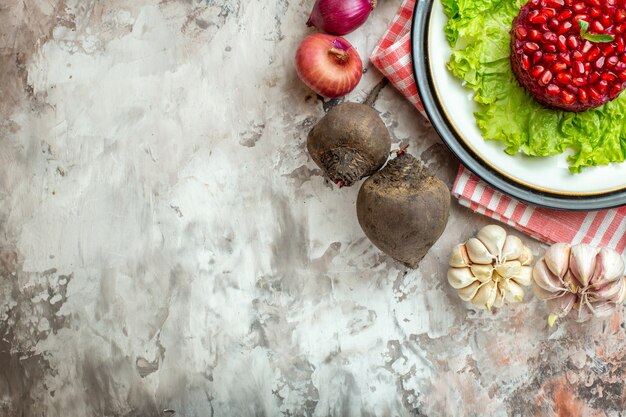 Draufsicht leckerer Granatapfelsalat auf grünem Salat mit frischem Gemüse auf hellem Hintergrund