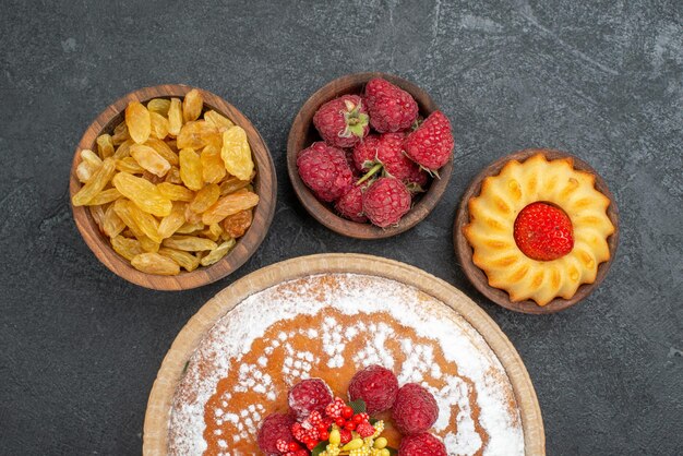 Draufsicht leckerer Himbeerkuchen mit Rosinen auf grauer Oberfläche Zuckerkekskuchen Keks Tee süße Torte