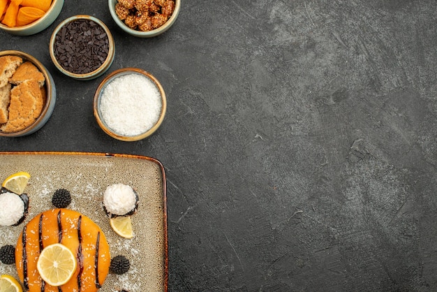 Draufsicht leckerer kleiner Kuchen mit Kokosbonbons auf dem dunklen Schreibtisch Kuchen Dessertkuchen Keks Teesüßigkeit