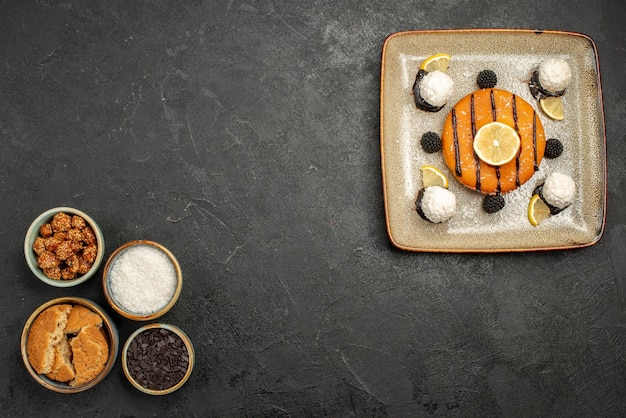 Draufsicht leckerer kleiner Kuchen mit Kokosbonbons auf dunkler Oberfläche Dessertkuchen Keks Teesüßigkeit