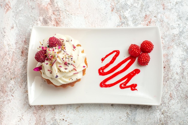 Draufsicht leckerer kleiner Kuchen mit Sahne und Himbeeren auf weißem Hintergrund Teekuchen Keks süße Sahne Dessert