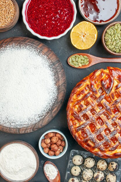 Draufsicht leckerer Obstkuchen mit Marmelade Nüssen und Mehl auf dem dunklen Dessertkuchen süßer Teekuchen Teig Keks backen Zucker