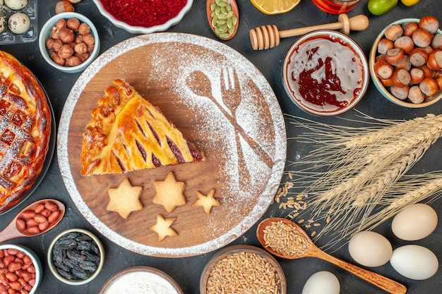 Draufsicht leckerer Obstkuchen mit Marmeladennüssen und Mehl auf dem dunklen Keks Dessertkuchen Teekuchenteig süßer Backzucker