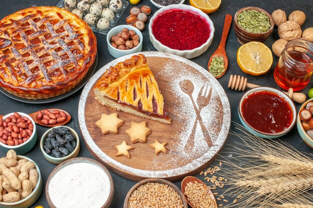 Draufsicht leckerer Obstkuchen mit Marmeladennüssen und Mehl auf dem dunklen Keks Dessertkuchen Teekuchenteig süßer Backzucker