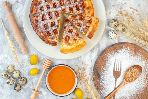 Draufsicht leckerer Obstkuchen mit Mehl auf weißem Tischkuchen süßer Teig Eier Zucker Tee Besteck Keks backen