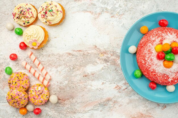 Draufsicht leckerer rosa Kuchen mit Keksen auf hellweißer Oberfläche Goodie Rainbow Candy Dessert Farbkuchen