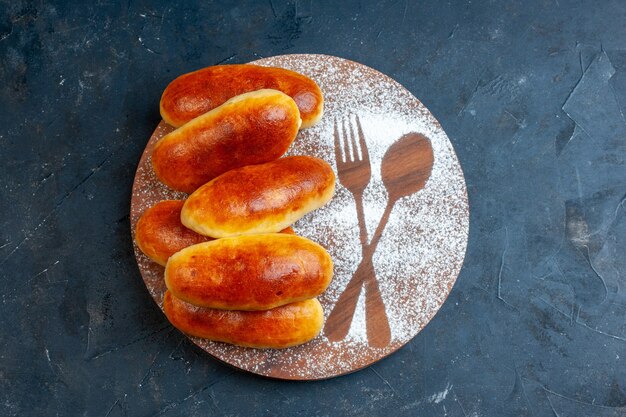 Draufsicht leckeres Abendessen Brötchen Gabel und Löffel Aufdruck in Puderzucker auf Holzbrett auf Tischkopierplatz