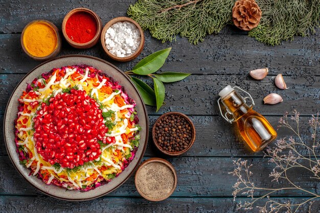 Draufsicht leckeres Essen appetitliches Weihnachtsessen und fünf Schüsseln mit bunten Gewürzen neben der Flasche Öl-Knoblauch-Fichtenzweige mit Zapfen