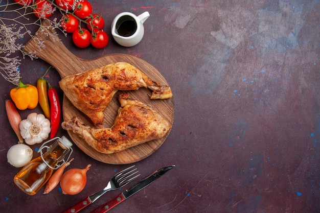 Draufsicht leckeres gebratenes Huhn mit frischem Gemüse und Gewürzen auf dunklem Hintergrundnahrungsmittelhühnermahlzeitgemüsefleisch