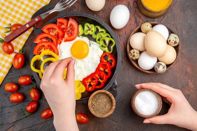 Draufsicht leckeres Omelette mit geschnittener Paprika und Gewürzen auf dem dunklen Tisch