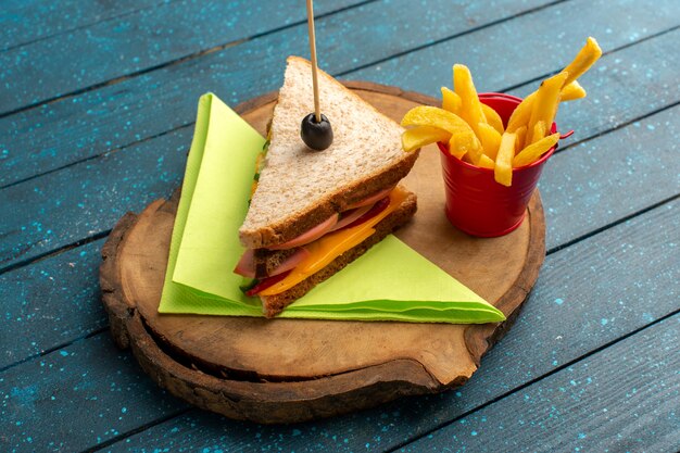 Draufsicht leckeres Sandwich mit Käseschinken innen mit Pommes Frites auf dem blauen Holzschreibtisch Sandwich-Essen Mahlzeit