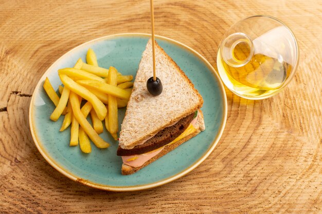 Draufsicht leckeres Sandwich mit Olivenschinken Tomaten Gemüse in Platte mit Pommes Frites und Öl auf dem hölzernen Hintergrund Sandwich Food Snack Frühstück Foto