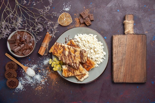 Draufsicht leckeres süßes Gebäck mit Schokolade und Hüttenkäse auf dunklem Schreibtischgebäckkekskuchenzuckersüßtee