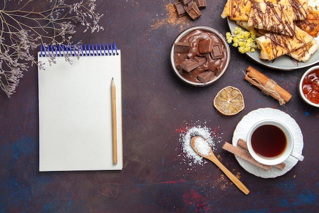 Kostenloses Foto draufsicht leckeres süßes gebäck mit tasse tee auf dunklem hintergrund gebäckkekskuchenzuckersüß