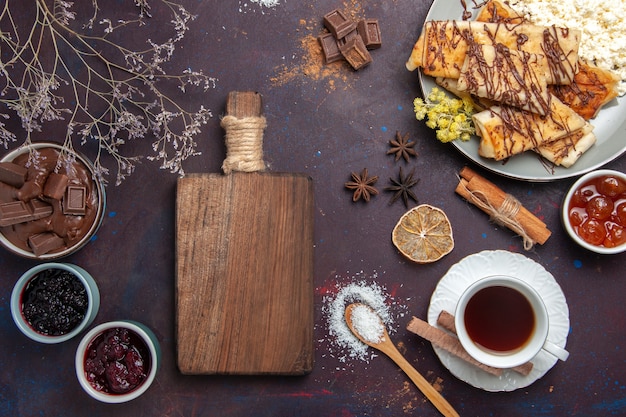 Draufsicht leckeres süßes Gebäck mit Tasse Tee und Marmelade auf dunklem Hintergrund Gebäckkekskuchenzuckersüßtee